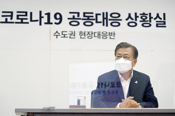 President Moon Jae-in listens to a briefing from officials of the National Medical Center at the hospital on Friday on the provision of sickbeds for serious cases of new coronavirus infection in the Seoul metropolitan area.  [YONHAP] 