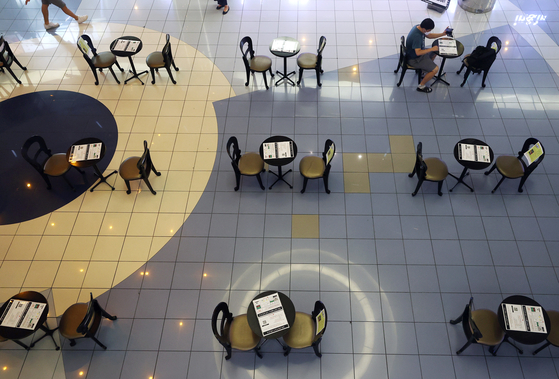 Tables are spaced out at a movie theater in downtown Seoul Wednesday, each with a pamphlet describing sanitation guidelines. [YONHAP]
