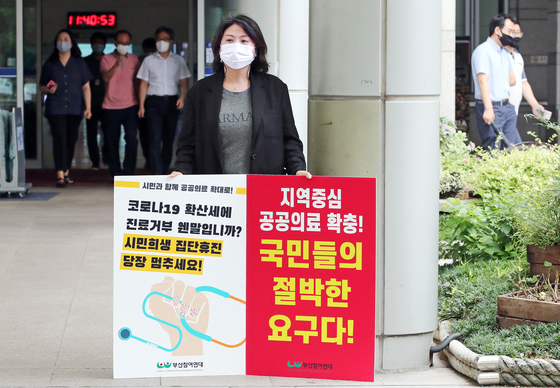 A member of the civic group Citizens' Solidarity for Participation of Busan holds a one-person picket protest in front of Busan City Hall, showing support for expanding regional health care services and urging doctors to halt their strike and return to treating patients amid the Covid-19 pandemic. [SONG BONG-GEUN] 