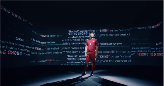 Park Ji-sung stands in a room with racist slogans projected on the walls in a new "Shoot For Love" video. [SCREEN CAPTURE]