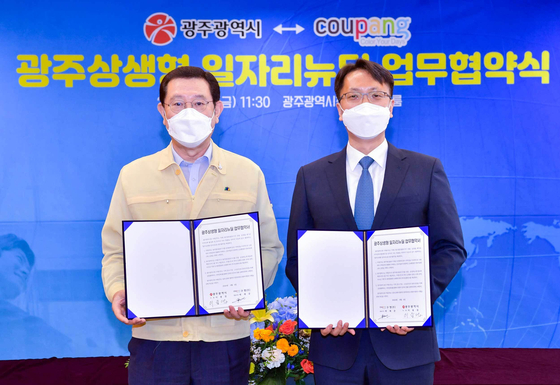 Gwangju Mayor Lee Yong-sup, left, and Park Dae-jun, representative director of the new business division at Coupang, are shown Friday signing an agreement to build a distribution center in Gwangju. [COUPANG]