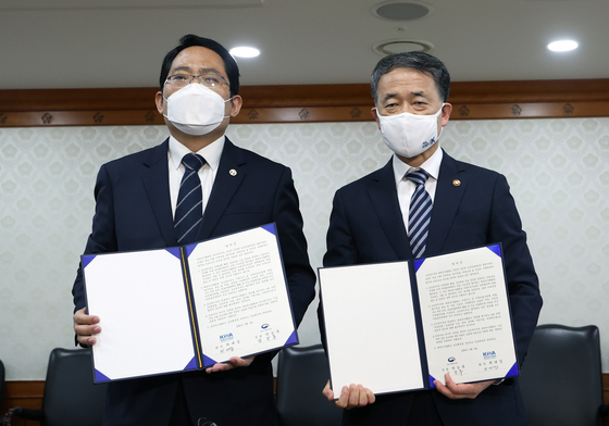 Korean Minister of Health and Welfare Park Neung-hoo, right, and Korean Medical Association President Choi Dae-zip hold up a signed agreement. The two sides agreed to end the strikes in exchange for the government suspending its plans. [YONHAP]