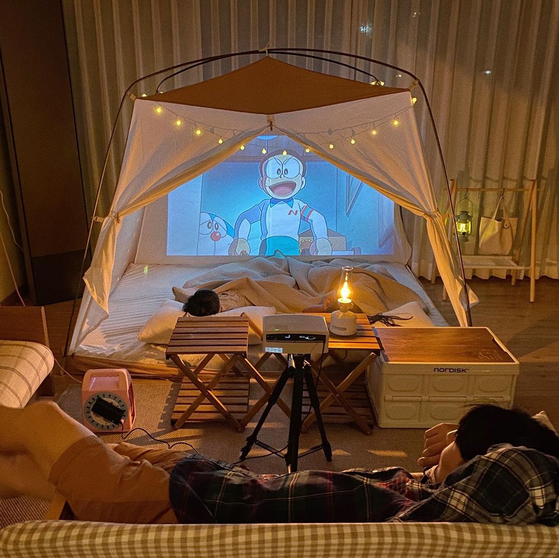 A growing number of people, especially families with children, enjoy camping at home by setting up a tent in the middle of the living room. [NAM JEONG-MIN]