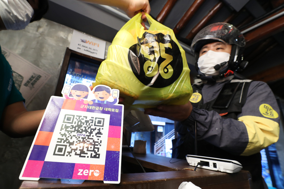 A deliveryman from Ddingdong, a delivery app participating in the Zero Delivery Union initiative, picks up an order from a restaurant in Jongno District, central Seoul. Seoul city launched the Zero Delivery Union service, which charges a 2 percent commission fee, in order to lessen the burden on the self-employed population. The service is initially available with seven small- and medium-sized delivery app companies. [YONHAP] 