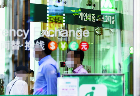 People pass by the window of a bank's physical branch in Seoul. [YONHAP]