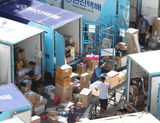 Delivery workers sort packages at a logistic center in Seoul. [NEWS1] 