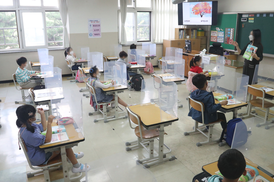 First graders at Wonil Elementary School in Suwon, Gyeonggi, return to their classroom Monday for the first time in nearly a month. Wonil was among some 7,000 schools in the greater Seoul area that were allowed to reopen Monday. [YONHAP]