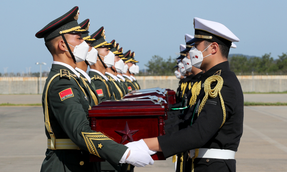 South Korean honor guards hand over caskets to Chinese guards at a ceremony at Incheon International Airport on Sunday. The caskets contain 117 sets of remains of Chinese soldiers killed during the 1950-53 Korean War. It was the seventh such repatriation ceremony. Of the remains repatriated Sunday, 103 sets were excavated last year from Arrowhead Ridge, a battle site inside the demilitarized zone separating the two Koreas. Others were uncovered in other parts of South Korea. Since the two countries agreed on the return of the Chinese troop remains in 2014 in a gesture of their friendship, Seoul has returned 716 sets of remains of Chinese soldiers, including the latest 117 sets.  [MINISTRY OF NATIONAL DEFENSE]