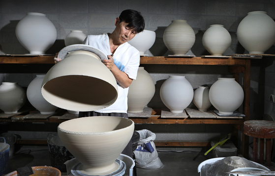 Ceramic artist Shin Chul assembles the upper part of a moon jar with the lower part at his ceramic studio Huguro-Bitzun-Dal, located in Icheon, Gyeonggi. [BY PARK SANG-MOON] 