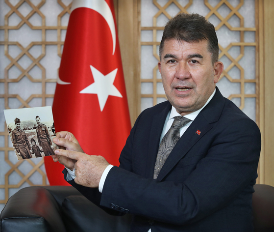 Ambassador of Turkey to Korea, Ersin Ercin, speaks with the Korea JoongAng Daily at the Embassy of Turkey in central Seoul on July 16. He is holding up a photo of Lieutenant Mehmet Gonenc and other soldier with a young Korean girl they found among the ruins of the war. [PARK SANG-MOON]