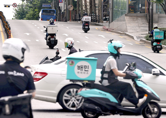 Delivery workers on motorcycles deliver food in Seoul, where online orders have sharply increased since the coronavirus outbreak began. [YONHAP]