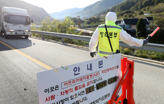 A government official blocks the entrance to a pig farm in Hwacheon County, Gangwon, after pigs supplied from this region were found infected by African swine fever on Friday. [YONHAP]