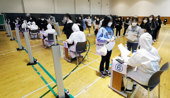 Students undergo body temperature checks before testing for an exam at Sungshin Women's University in central Seoul on Sunday. [YONHAP]