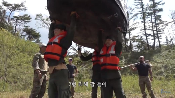 ’Fake Men“ recruits carry a boat as part of training. [YOUTUBE]