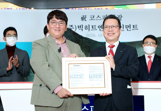 Big Hit Entertainment Chairman Bang Si-hyuk, left, and Korea Exchange CEO and Chairman Jung Ji-won pose for a photo holding a memorial tablet celebrating the company's public listing on Oct. 15 at the exchange's headquarters in Yeouido, western Seoul. [BIG HIT ENTERTAINMENT]