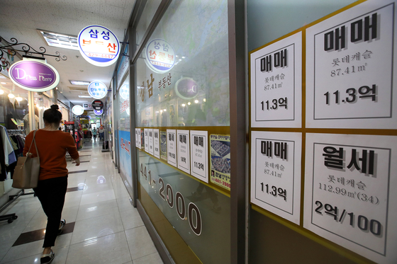 A woman passes by a real estate agency near Gangdong Lotte Castle First apartment complex in Gangdong District, eastern Seoul. No jeonse offers are posted. [JANG JIN-YOUNG]