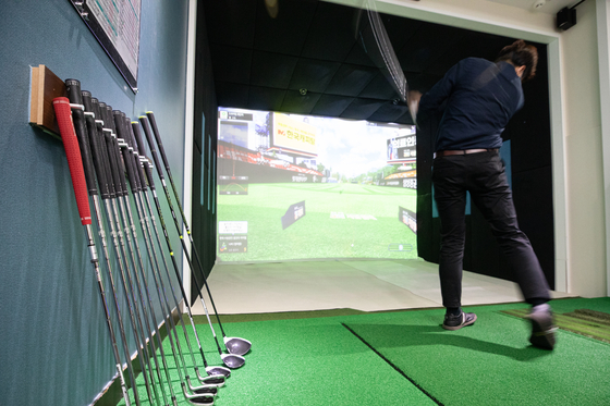 A golfer practices at a screen golf practice center in Seoul on Oct. 13. [YONHAP]
