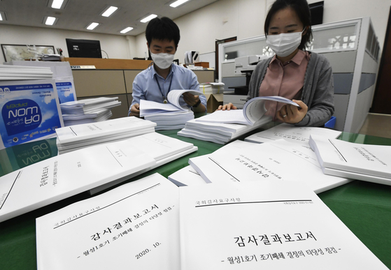 National Assembly workers look at copies of a report submitted by the Board of Audit and Inspection on the government's decision to shut down the Wolsong I nuclear reactor. [YONHAP] 
