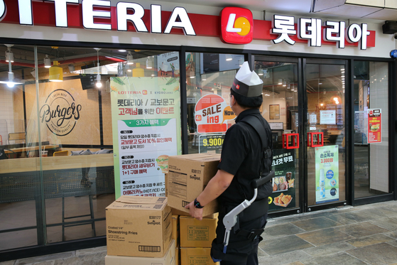 A Lotteria employee carries heavy boxes wearing a wearable robot that lightens the weight of the boxes. [LOTTE GRS] 
