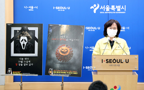 Park Yoo-mi, the Seoul city government’s director of public health, on Wednesday shows posters made by the city to discourage potential revelers from celebrating Halloween over the weekend. [YONHAP]