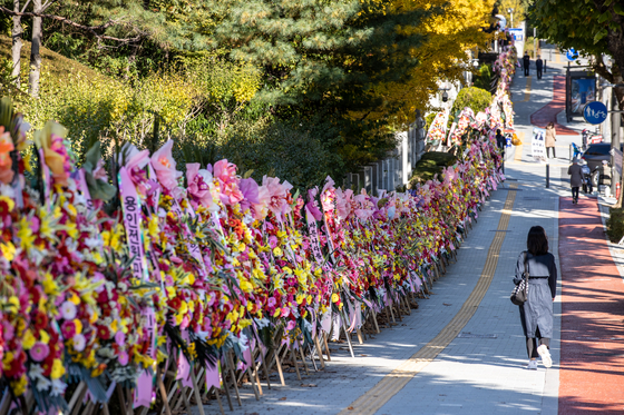 Flower wreathes sent by the people who support Prosecutor General Yoon Seok-youl stand along the pedestrian walkway in front of the Supreme Prosecutors' Office in Seocho District of southern Seoul on Oct. 29. Conservative civic groups who sent the majority of flowers removed them on Monday as controversy about Yoon's political future grew.  [YONHAP] 〉