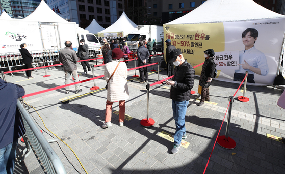 People practice social distancing Sunday at Seoul Plaza while waiting in line to purchase hanwoo (Korean beef) at special prices. The event lasts through Tuesday. [YONHAP]