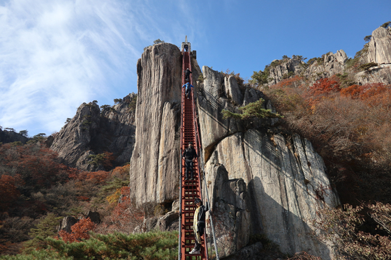 Visitors to the red staircase in Mount Daedun in Wanju County, North Jeolla, walk up, hands tightly holding onto the handles on both sides. [LEE SUN-MIN]