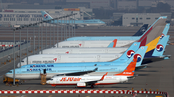 Korean Air and Asiana planes parked at Incheon International Airport on Monday. Korean Air will be acquiring Asiana with help from KDB. [YONHAP]