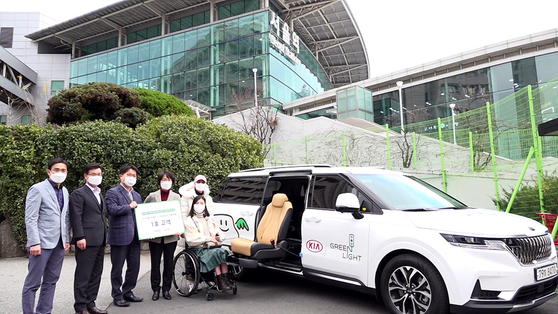 Employees at Korea Railroad pose in front of the first modified vehicle for the disabled after signing a memorandum of understanding (MOU) with Kia Motors on Monday. From 2021, the partner companies will sponsor for two years round-trip KTX tickets and the customized vehicle as well as transportation expenses for 500 families with family members with disabilities. [YONHAP]