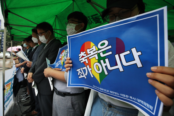 Protestors hold a card reading ″A blessing is not a sin″ on June 24 in front of the Korean Methodist Church headquarters in Gwanghwamun, central Seoul, demanding the church revoke its decision to suspend Lee. [YONHAP]