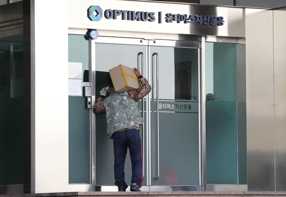 A delivery worker takes a peek at the closed doors of Optimus Asset Management's office in Gangnam, southern Seoul on October 13. [NEWS1]