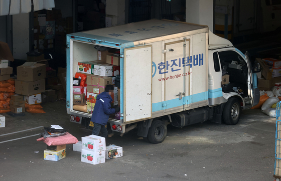 A delivery worker organizing packages inside a delivery truck in Seoul on Tuesday. [YONHAP]