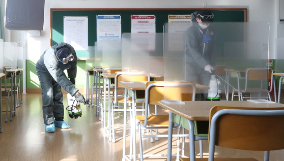 Workers disinfect a classroom at Ulsan Joongang High School in Ulsan Tuesday, two days before it will be used as a testing site for the College Scholastic Ability Test (CSAT). [YONHAP] 