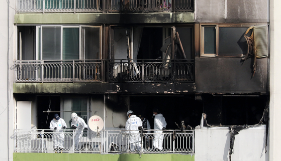 Police and firefighters inspect Wednesday the scene of a fire at an apartment building in Gunpo, Gyeonggi, which led to 11 casualties including four deaths. [NEWS1]