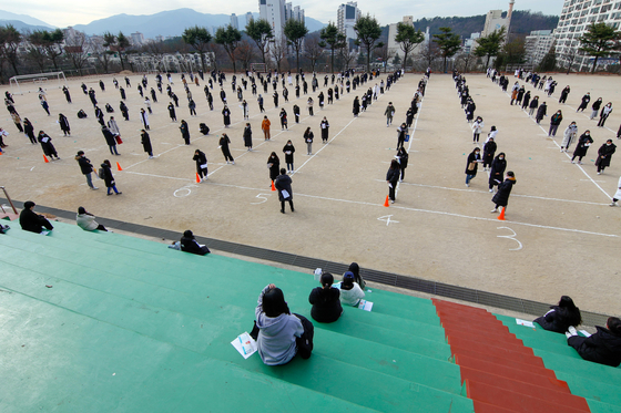 High school seniors gather at Junghwa Girls High School in Daegu Wednesday, a day before the College Scholastic Ability Test, to listen to instructions about the exam while practicing social distancing. [YONHAP] 