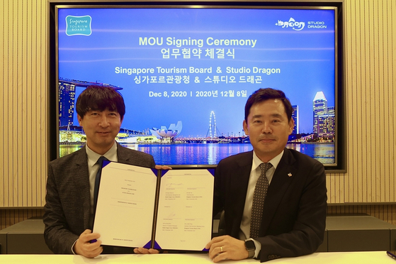 Yoo Bong-yeol, the head of content IP department, left, and CEO Kang Chul-gu of Studio Dragon pose for the camera with the memorandum of understanding signed by the local production house and the Singapore Tourism Board. [SINGAPORE TOURISM BOARD]