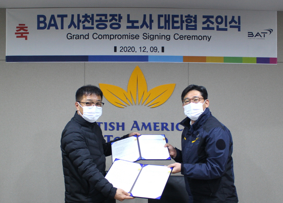Kang Seung-ho, head of BAT Korea’s Sacheon factory, right, and Koo Sung-il, head of the labor union, pose during a compromise signing ceremony which was held at the factory in South Gyeongsang on Wednesday. [BAT KOREA]