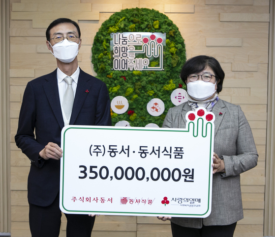 Choi Sang-in, associate vice president of Dongsuh Foods, left, and Kim Youn-soon, secretary general of Community Chest of Korea, during the donation event held in central Seoul on Thursday. [DONGSUH]