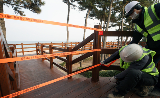 Officials in Gangneung, Gangwon, close off walking trails along Gyeongpo Beach Wednesday as the city prepares to block access to all its major tourist destinations to prevent possible transmission of the coronavirus. [YONHAP] 