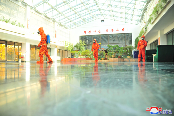 Health workers disinfect a government-run technology institute in Pyongyang on Dec. 16, in this photograph from North Korean state media. [YONHAP]