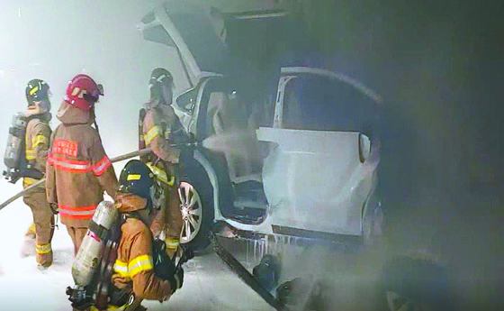 Firefighters extinguish a Tesla Model X electric car that caught fire in an underground parking garage in Seoul on Dec. 9. The accident killed one person and injured two. [YONGSAN FIRE STATION]