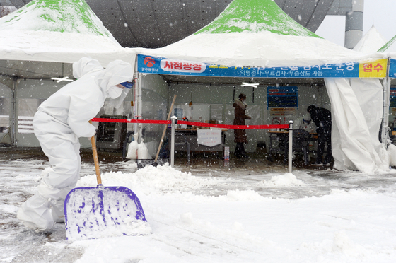 A health official clears snow at a Covid-19 testing site in Gwangju Wednesday morning as the city saw some 14 centimeters (5.5 inches) of snow. [NEWS1]