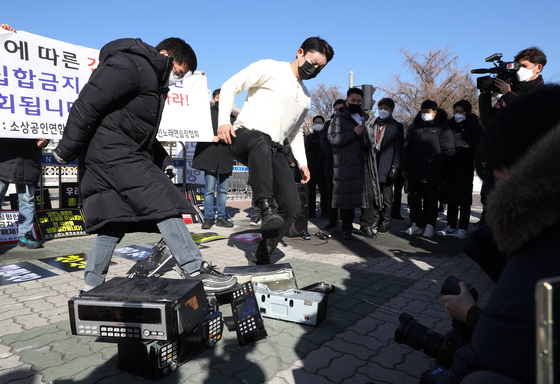In front of the National Assembly on Wednesday, owners of coin noraebang, or booth-type singing rooms, stage a press event at which they destroy singing room equipment to protest the government’s social distancing measures. They pledged they will not obey any shutdown order after Jan. 18. [NEWS1]