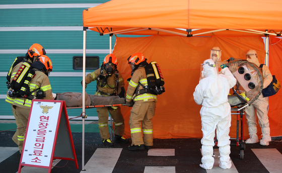 Health workers and emergency responders take part in a training exercise at a makeshift Covid-19 treatment center set up in Eunpyeong District, northern Seoul, on Wednesday. [YONHAP]