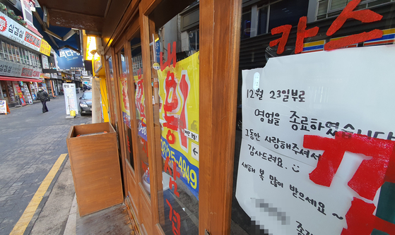 A sign announcing the close of business on Dec. 23, 2020, posted on an empty restaurant in downtown Seoul on Thursday. Many businesses either folded or are planning to do so due to the government’s strict social distancing while the third wave of Covid-19 continues. [YONHAP]