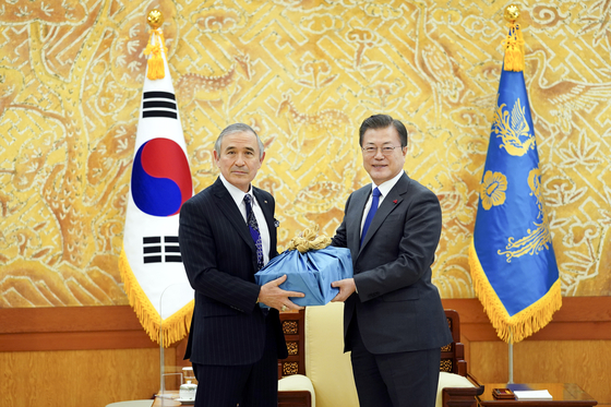 President Moon Jae-in, right, presents outgoing U.S. Ambassador to Korea Harry Harris with a farewell gift of Andong soju at the Blue House in central Seoul Tuesday. [BLUE HOUSE]