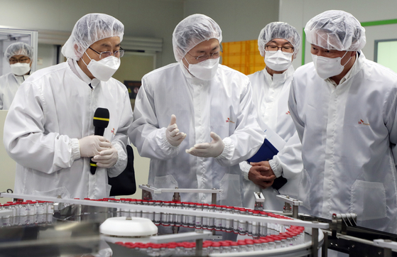President Moon Jae-in, center, talks with SK Group Chairman Chey Tae-won, far right, Wednesday while touring a SK Bioscience factory in Andong, North Gyeongsang. [YONHAP]