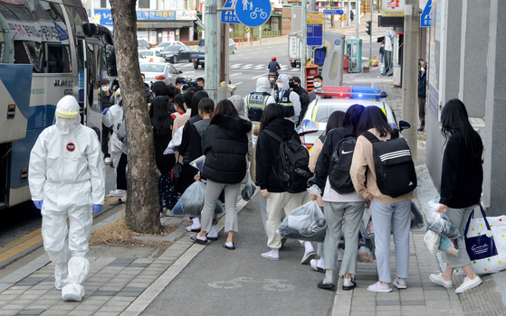 Students who were diagnosed with the coronavirus at the IEM School in Daejeon, a Christian missionary training school, board a bus Monday to be transferred to a nearby life treatment center for Covid-19 patients with mild or no symptoms. [KIM SEONG-TAE] 