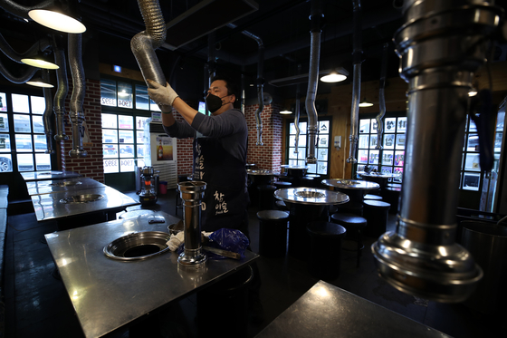 An owner of a restaurant in Dobong District, northern Seoul, on Thursday prepares for opening. Self-employed businesses, including bakeries, coin noraebang (booth-type singing rooms), cafes, restaurants and indoor gyms, gather in front of the Blue House on Thursday asking the government to end the prohibition on business from 9 p.m. to midnight, pushing for compensation for losses. [YONHAP]