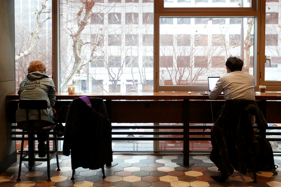 Customers at a coffee chain in Jung District, central Seoul, are drinking coffee indoors while maintaining distance on Jan. 18, when the relaxed social distancing measures started to permit indoor dining at coffee chains. [JANG JIN-YOUNG]